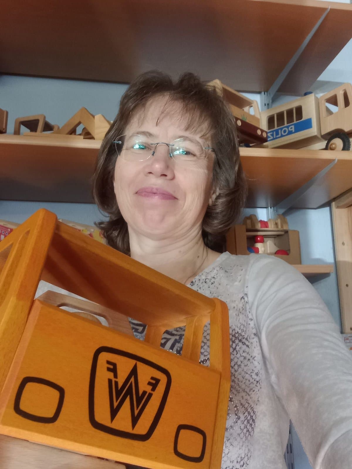 Inhaberin mit Holz-LKW vor dem Spielzeugregal