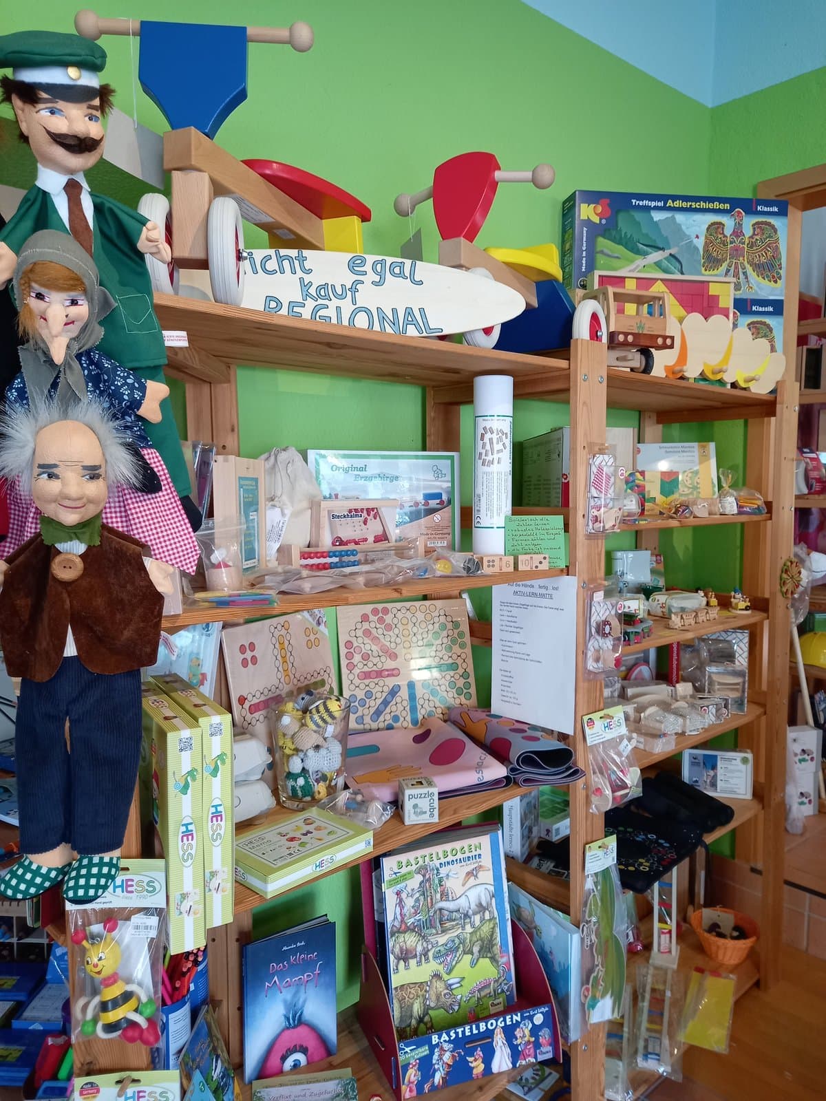 Handpuppen und regionale Holzspiele im Regal — „Kauf REGIONAL“