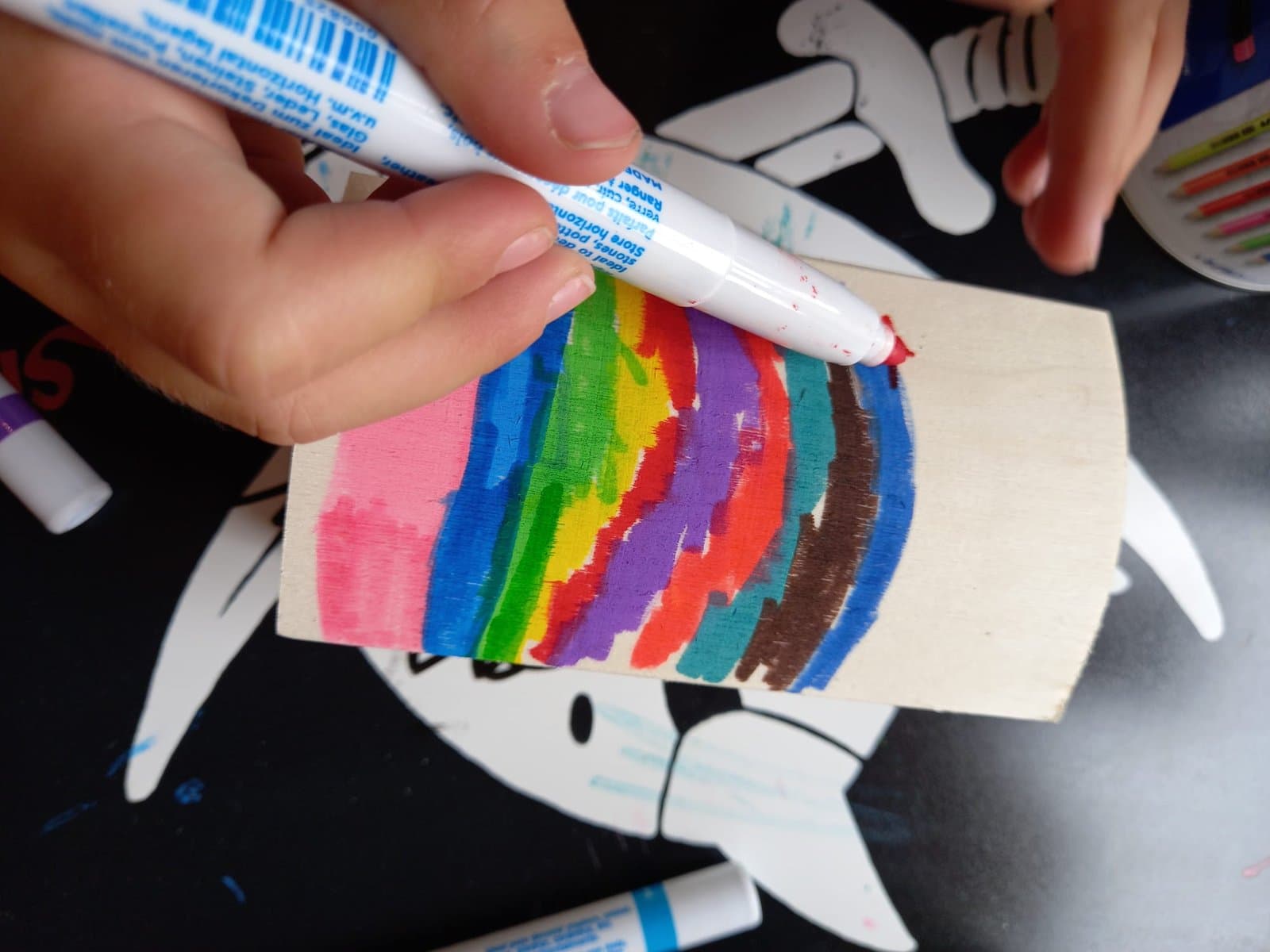Kinderhand bemalt eine Tanne auf Holz